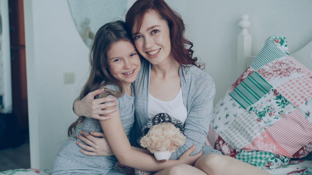 pexels-photo-36765438-36765438 A joyful mother and daughter hugging on a bed, sharing smiles and warmth.