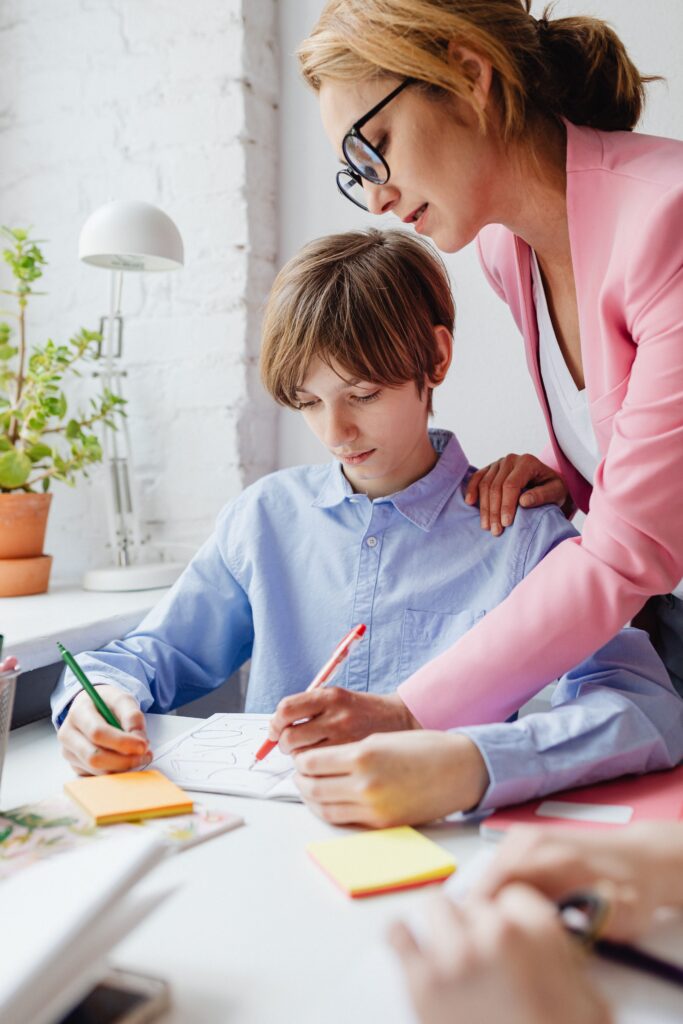 pexels-photo-7692514-7692514 Teacher helping a student with homework at a desk indoors.